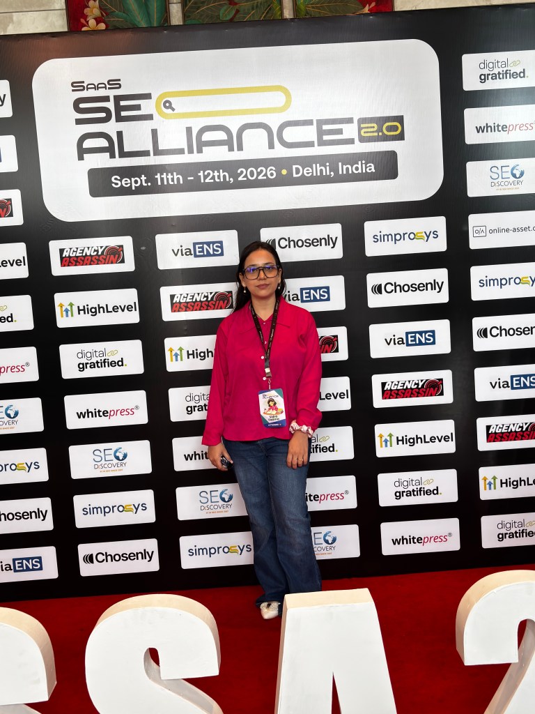 A person posing in front of a promotional backdrop for the SAAS SEO Alliance event, scheduled for September 11-12, 2026, in Delhi, India. The backdrop features various logos and sponsors related to digital marketing and SEO.